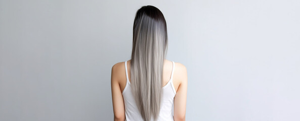 The rear view of a young woman with sleek, silver long hair, photographed in a studio with a white background and professional lighting. Generative AI.