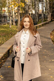 Fototapeta Konie - Red-haired girl in coat. Office worker, schoolgirl or student