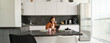 © Mix and Match Studio - Portrait of young woman, student sitting in kitchen with tablet and notebook, reading news online, studying remotely, e-learning at home