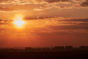 Wall Mural - The setting sun casts a warm glow over the city, as the sky turns shades of orange and red.