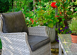 Fototapeta Tulipany - fotel rattanowy na tarasie w ogrodzie, sitting area in the garden, Recreation area in garden, wiklinowy fotel ogrodowe i stolik kawowy, rattan garden armchair	