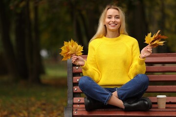 Sticker - Happy woman with autumn leaves on bench in park. Space for text