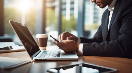 Close up businessman sitting at office in front of laptop and using smart phone
