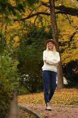 Canvas Print - Happy woman wearing warm sweater walking in autumn park