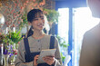 花屋でタブレットを使用して接客を行う日本人女性のスタッフ