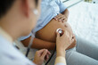 © DG PhotoStock - Asian male doctor visit to African - American pregnant woman patient home to talk and check for pregnancy health. On site - home medical service concept.