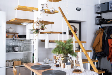 Festive Christmas decor in white kitchen, white modern loft interior with a metal modular ladder with wooden steps. New Year, mood, cozy home.