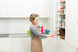 © Angelov - Weekend homework. Young pretty woman cleans in cozy living room at home. A beautiful woman in home clothes and rubber gloves in a bright room.