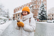 © mdyn - Beautiful stylish woman in hat walking on Market Square in Krakow in winter day and holding mobile phone. Urban lifestyle concept. Check social networks, book hotel. Winter holidays concept
