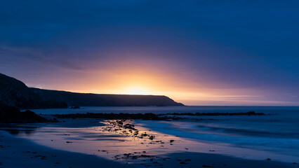 Canvas Print - Beautiful sunrise landscape image of Kennack Sands in Cornwall UK wuth dramatic moody clouds and vibrant sunburst