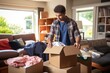 Man student sorts cardboard boxes with belongings standing in living room with scattered things