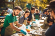 Team of Young Volunteers Helping in a Local Community Food Bank, Preparing Free Meal Rations to Low-Income People in a Park on a Sunny Day, Charity Workers Work in Humanitarian Aid Donation Center