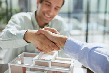 Wall Mural - handshake against the background of a model of a house under construction. client and designer