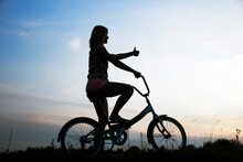 Silhouette Of A Girl On A Bicycle In Nature
