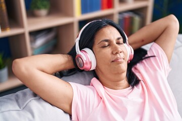 Wall Mural - Middle age hispanic woman listening to music relaxed on sofa at home