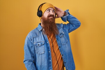 Poster - Caucasian man with long beard listening to music using headphones smiling confident touching hair with hand up gesture, posing attractive and fashionable