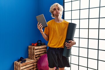 Poster - Young man holding yoga room puffing cheeks with funny face. mouth inflated with air, catching air.