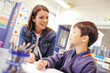 © Austockphoto - Aboriginal school teacher sitting with a school boy in the classroom