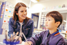 Aboriginal School Teacher Sitting With A Boy In The Classroom