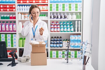 Sticker - Young blonde woman pharmacist holding pills bottle talking on smartphone at pharmacy