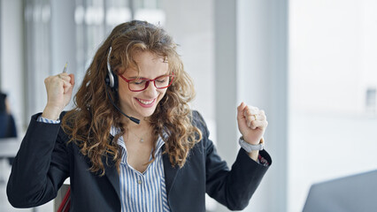 Poster - Young woman business worker using laptop and headphones celebrating at the office