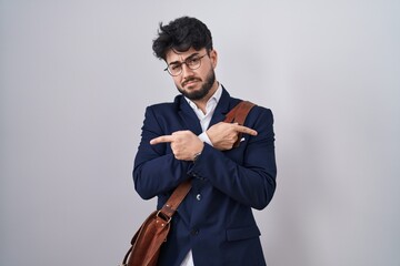 Poster - Hispanic man with beard wearing business clothes pointing to both sides with fingers, different direction disagree