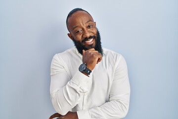 Poster - African american man standing over blue background with hand on chin thinking about question, pensive expression. smiling and thoughtful face. doubt concept.