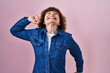 Middle age woman standing over pink background stretching back, tired and relaxed, sleepy and yawning for early morning