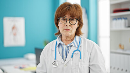 Wall Mural - Middle age woman doctor standing with serious expression at clinic