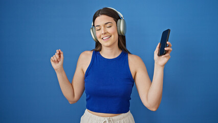 Poster - Young beautiful hispanic woman listening to music and dancing over isolated blue background