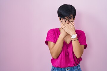 Canvas Print - Young asian woman with short hair standing over pink background shocked covering mouth with hands for mistake. secret concept.