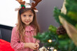 © Krakenimages.com - Adorable blonde girl wearing reindeer ears decorating christmas tree at home