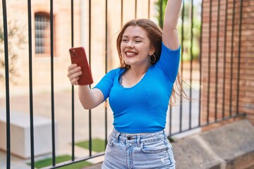 Sticker - Young redhead woman using smartphone with winner expression at street