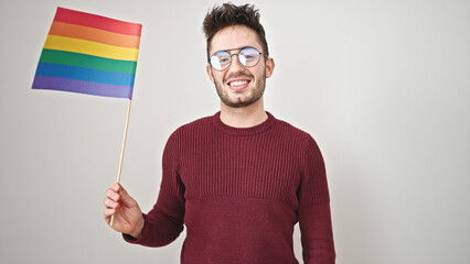 Wall Mural - Young hispanic man smiling confident holding rainbow flag over isolated white background