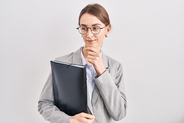 Canvas Print - Young caucasian woman wearing business clothes and glasses looking confident at the camera smiling with crossed arms and hand raised on chin. thinking positive.