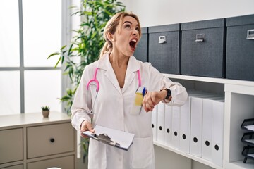 Poster - Hispanic doctor woman looking at the watch angry and mad screaming frustrated and furious, shouting with anger looking up.