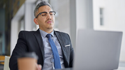 Sticker - Young hispanic man business worker wearing glasses using laptop at office