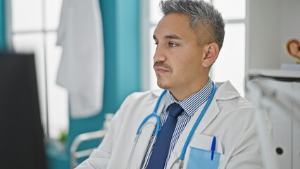 Wall Mural - Young hispanic man doctor using computer working at clinic