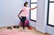 © Krakenimages.com - African american woman wearing medical mask stretching legs at sport center