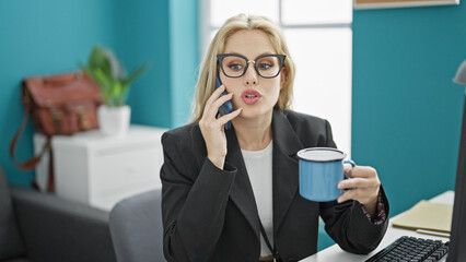 Wall Mural - Young blonde woman business worker talking on smartphone drinking coffee at the office