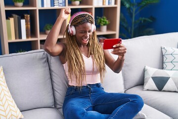 Poster - African american woman playing video game sitting on sofa at home