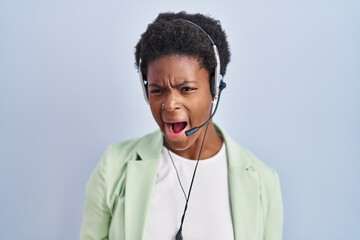 Sticker - African american woman wearing call center agent headset angry and mad screaming frustrated and furious, shouting with anger. rage and aggressive concept.