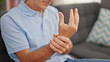 Middle age man sitting on sofa suffering for wrist pain at home