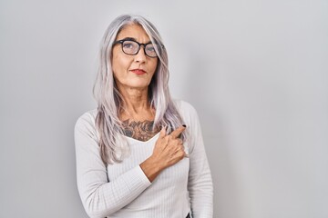 Canvas Print - Middle age woman with grey hair standing over white background cheerful with a smile on face pointing with hand and finger up to the side with happy and natural expression