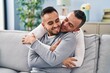 © Krakenimages.com - Two men couple hugging each other sitting on sofa at home