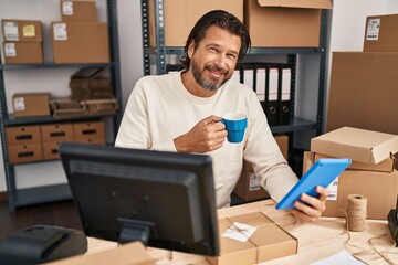 Canvas Print - Middle age man ecommerce business worker using touchpad drinking coffee at office