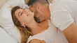 © Krakenimages.com - Man and woman couple lying on bed together kissing at bedroom