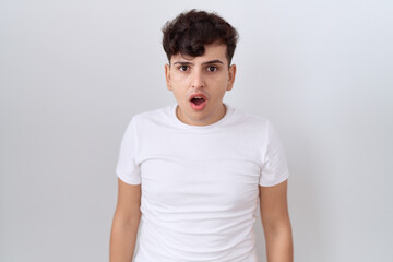 Sticker - Young non binary man wearing casual white t shirt afraid and shocked with surprise and amazed expression, fear and excited face.