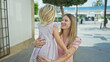 © Krakenimages.com - Cheerful caucasian mother and daughter embracing a warm, loving hug, sitting on a city bench, laughing, and smiling together, filled with joy and happiness, outdoors on a sunny street.