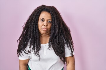 Poster - Plus size hispanic woman standing over pink background looking sleepy and tired, exhausted for fatigue and hangover, lazy eyes in the morning.